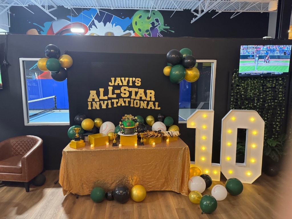 All-star birthday dessert table with cake, trophies, and marquee lights at SWING